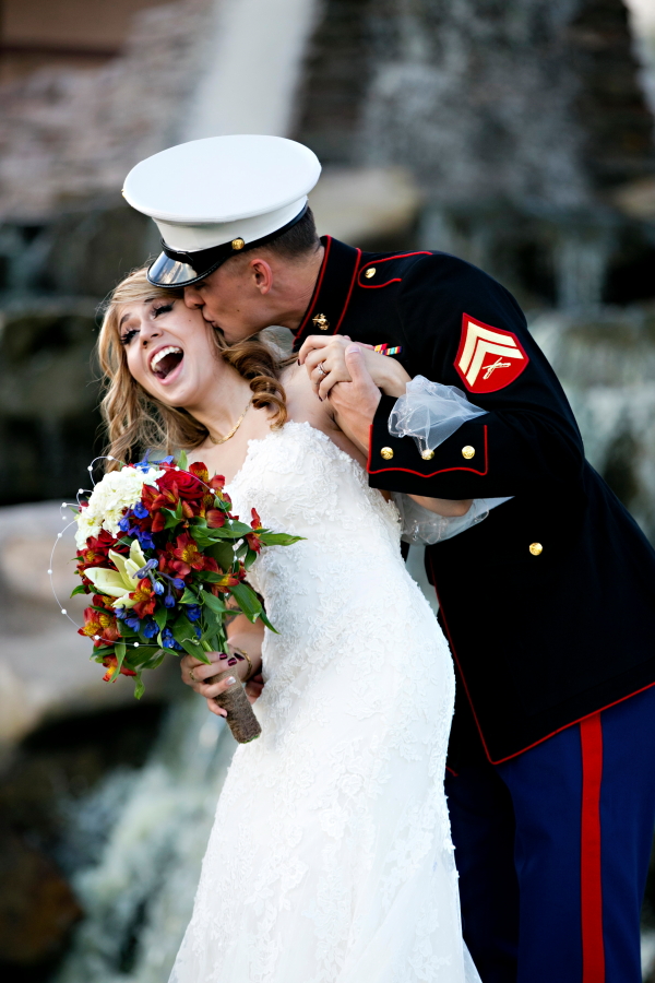 Groom is military and playfulling kissing the brides cheek.  Groom being playful with Bride.